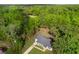 An aerial view of the house, featuring the roof, driveway, and surrounding forest trees at 6 Fisher Way Pl, Ocklawaha, FL 32179