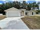 Newly built home with a gray garage door and a small lawn at 1 Pine Trace Trl, Ocala, FL 34472