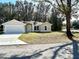 Tan house with white trim, gray garage door, and a landscaped yard at 1 Pine Trace Trl, Ocala, FL 34472