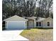 Tan house with a white garage door and front yard at 1 Pine Trace Trl, Ocala, FL 34472