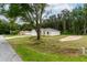 Exterior view of a home with a well-kept lawn and a driveway, surrounded by mature trees and greenery at 1 Pine Trace Trl, Ocala, FL 34472