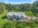 Stunning aerial view of a pink home with mature trees and manicured landscaping on a sprawling lot with red outbuildings at 11831 Sw Highway 484, Dunnellon, FL 34432