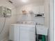 Well-lit laundry room with washer, dryer, utility sink, and storage shelving at 11831 Sw Highway 484, Dunnellon, FL 34432