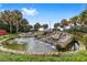 Scenic community water feature with small waterfalls and lush landscaping with flowering plants at 14550 Sw 61St Ct, Ocala, FL 34473