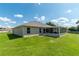 Back exterior view with a screened lanai and large windows overlooking the beautiful landscaped backyard at 25 Nw 45Th Loop, Ocala, FL 34475