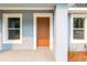 Welcoming front porch with a stylish brown door and two windows offering lots of natural light at 13625 Sw 107 Pl, Dunnellon, FL 34432