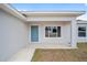 Welcoming front entrance with a covered porch, light blue door, and a view of the landscaping at 24381 Nw Falcon Ave, Dunnellon, FL 34432