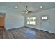 Bright living room featuring wood-look floors, ceiling fan, and a window letting in natural light at 202 Guava Pass, Ocklawaha, FL 32179