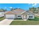 Tan one-story house with white garage door and shutters, and a green lawn at 4414 Sw 170Th Street Rd, Ocala, FL 34473