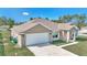 Tan one-story house with white garage door and shutters, and a green lawn at 4414 Sw 170Th Street Rd, Ocala, FL 34473