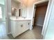 Bright bathroom featuring double vanity with white cabinets and black hardware, with open closet space at 13374 Sw 63Rd Ter, Ocala, FL 34473