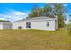 View of the home's backyard featuring a lawn and the home's gray exterior at 4030 Se 134Th St, Belleview, FL 34420