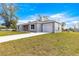 Side view of a gray single story home with a well manicured lawn and a concrete driveway at 4030 Se 134Th St, Belleview, FL 34420