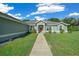Charming single-story home with a red front door, beautiful landscaping, and a well-manicured lawn under a bright sky at 1934 Nw 79Th Loop, Ocala, FL 34475