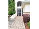 Inviting front entrance with a white security door, well-kept landscaping, and a brick paver walkway at 17808 Se 115Th Ct, Summerfield, FL 34491