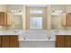 Luxurious bathroom featuring double vanities, a soaking tub, and a decorative window at 11017 Sw 71St Cir, Ocala, FL 34476
