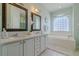 Bright bathroom features a double vanity, soaking tub with tile surround, and decorative mirrors at 15268 Sw 14Th Avenue Rd, Ocala, FL 34473