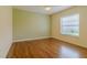 This bedroom has neutral walls, wood floors, a ceiling fan and a window overlooking the yard at 15268 Sw 14Th Avenue Rd, Ocala, FL 34473