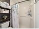Bright bathroom featuring a shower with a leafy curtain, toilet, and wooden shelf with towels and toiletries at 4011 Se 47Th Pl, Ocala, FL 34480