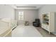 Well-lit Bedroom with a crib, armchair and built-in shelving at 5172 Nw 46Th Lane Rd, Ocala, FL 34482