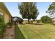 A sprawling backyard features a screen enclosed patio, lush grass, a mature tree, and well manicured landscaping at 8463 Sw 84Th Loop, Ocala, FL 34481