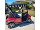 Red golf cart with black-and-white striped canopy parked outside at 12333 Se 177Th Loop, Summerfield, FL 34491