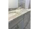 A stylish bathroom vanity featuring gray cabinets and a granite countertop with double sinks at 3 Dogwood Trl, Ocala, FL 34472