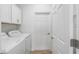 Laundry room with white washer and dryer, storage cabinets, and a door to outside access at 7709 Sw 86Th Ct, Ocala, FL 34481