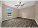 Bright bedroom featuring wood-look flooring, a ceiling fan, and a view to the backyard at 706 Stanley Ave, Wildwood, FL 34785