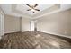 Spacious main bedroom featuring tray ceilings, a ceiling fan, and stylish wood-look flooring at 706 Stanley Ave, Wildwood, FL 34785