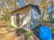 Gray storage shed with black door, landscaping, and water tank at 7131 Sw 19Th Avenue Road Rd, Ocala, FL 34476