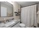 Modern bathroom with a granite vanity top, framed mirror, dark shelves, and a shower with patterned curtain at 7336 Sw 131St Ln, Ocala, FL 34473