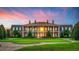 Stunning brick estate with manicured lawn, symmetrical landscaping, and beautiful architectural details at sunset at 17800 Se 237Th Ct, Umatilla, FL 32784