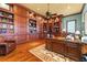 Spacious home office with custom built-in wooden shelves and cabinets, ceiling fan, and leather chair at 17800 Se 237Th Ct, Umatilla, FL 32784