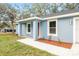 A covered front porch with gray columns and a concrete walkway leading to the brown front door at 13374 Sw 112 St, Dunnellon, FL 34432