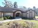 Exterior view of a home with a landscaped yard and an arched entryway at 4215 Se 24Th Ter, Ocala, FL 34480