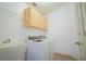 Functional laundry room with white washer and dryer, utility sink, overhead cabinetry, and wood-look flooring at 4215 Se 24Th Ter, Ocala, FL 34480