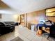 Living room featuring neutral walls, wood paneling, and tile floors; desk and furniture included at 34828 1St Ave, Leesburg, FL 34788