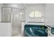 Bathroom featuring a glass-enclosed shower and a tub with decorative green tiling at 4893 Sw 4Th Cir, Ocala, FL 34471