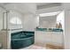 Well-lit bathroom featuring a tub with a dark green surround, and double vanity at 4893 Sw 4Th Cir, Ocala, FL 34471