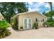 Separate outbuilding with double doors and a window, surrounded by lush greenery and flowers at 4893 Sw 4Th Cir, Ocala, FL 34471