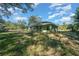 View of the green home featuring well-maintained lawn and mature trees under a cloudy blue sky at 19662 Sw Marine Blvd, Dunnellon, FL 34431