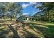 Green home features a covered patio with multiple windows and a spacious lawn, providing natural light at 19662 Sw Marine Blvd, Dunnellon, FL 34431