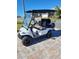 White golf cart with black seats is parked on a brick driveway on a sunny day at 9617 Sw 102Nd Ter, Ocala, FL 34481