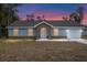 House exterior at dusk showcasing gray siding, stone accents, and a 1-car garage at 13526 Sw 106Th Pl, Dunnellon, FL 34432