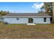 Single story house back view, gray siding, sliding glass door, small patio, and grassy yard at 13526 Sw 106Th Pl, Dunnellon, FL 34432