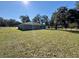 Grassy backyard with a view of the home, bordered by a fence and mature trees at 9285 Se Highway 42, Summerfield, FL 34491