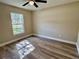 Bedroom features new wood-look flooring, ceiling fan, and a large window overlooking the backyard at 9285 Se Highway 42, Summerfield, FL 34491