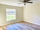 Bedroom with wood-look floors, ceiling fan, and a window overlooking the front yard at 9285 Se Highway 42, Summerfield, FL 34491