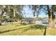 Exterior home view showcases a lush green yard, mature trees, and a charming covered entrance at 9285 Se Highway 42, Summerfield, FL 34491